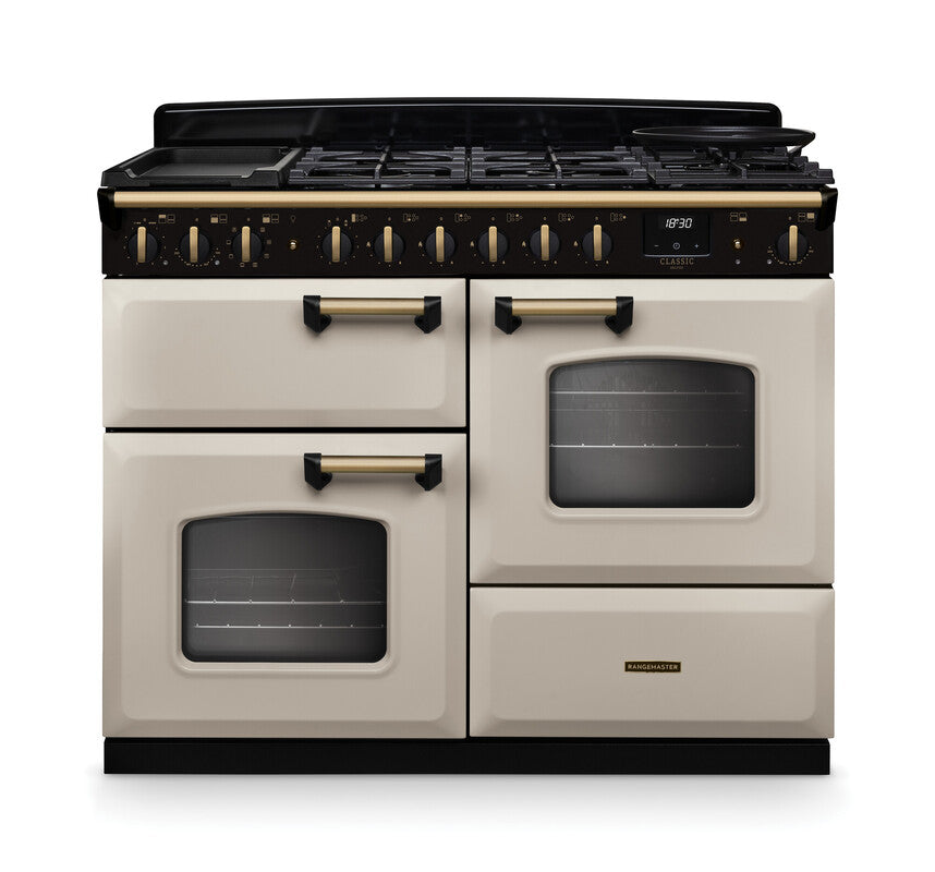 Rangemaster Classic Deluxe 110 dual fuel cooker in cream with antique brass handles and trim, front view.
