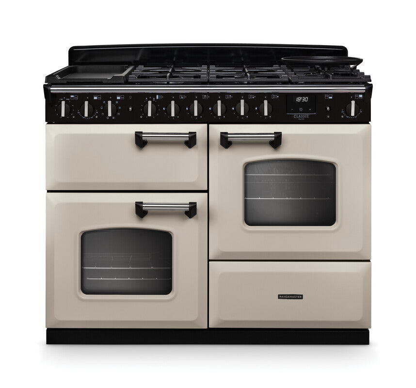 Rangemaster Classic Deluxe 110 dual fuel cooker in cream with chrome trim, six burners, and two ovens visible front view.