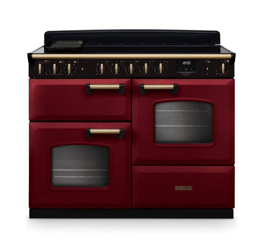 Rangemaster Classic Deluxe 110 induction cooker in red with antique brass handles and trim, front view.