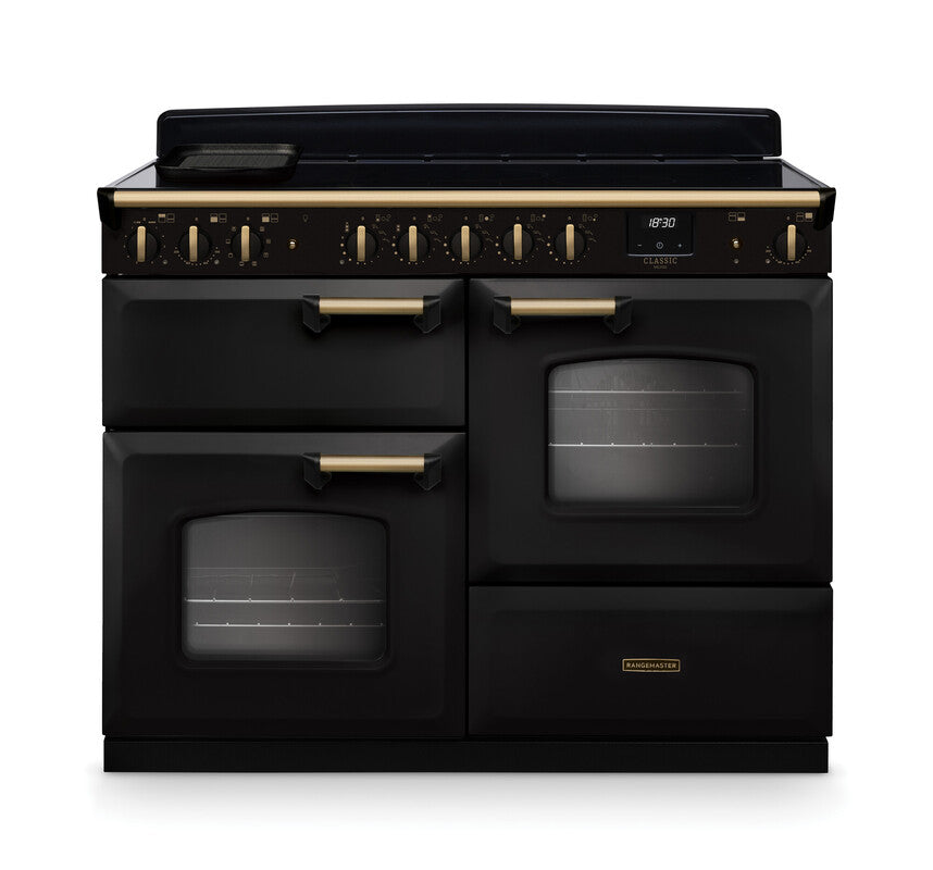 Rangemaster Classic Deluxe 110 induction cooker in black with antique brass trim and dual ovens visible front view.
