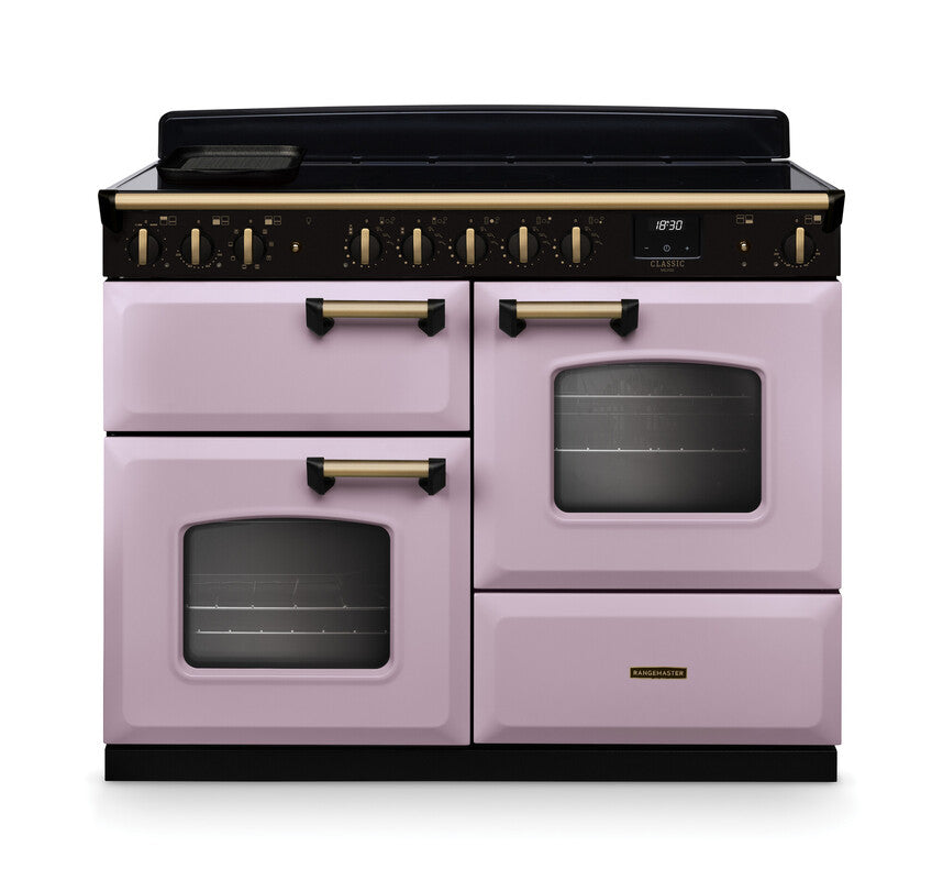 Rangemaster Classic Deluxe 110 induction cooker in pastel pink with antique brass handles and black control panel