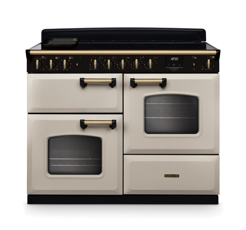 Rangemaster Classic Deluxe 110 induction cooker in cream with antique brass trim and multiple ovens visible front view.