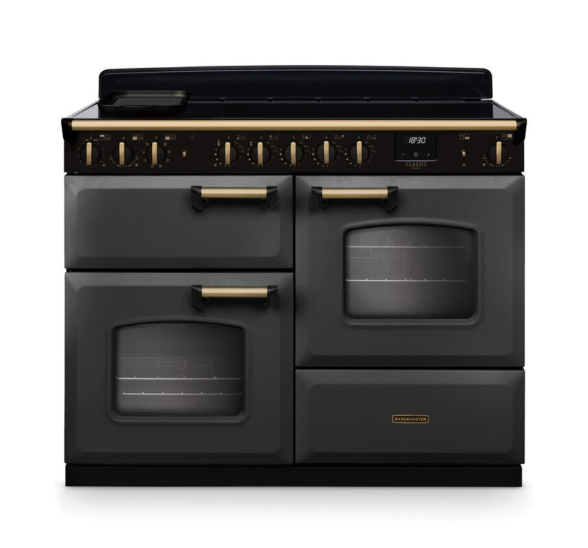 Rangemaster Classic Deluxe 110 induction cooker in black with antique brass trim and control knobs, front view.
