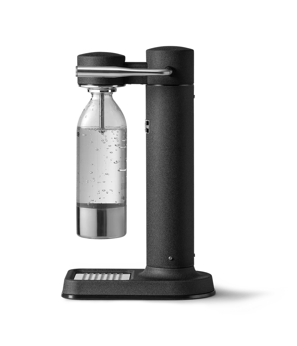 Aarke Carbonator 3 matte black soda maker with clear bottle filled with sparkling water on a drip tray.