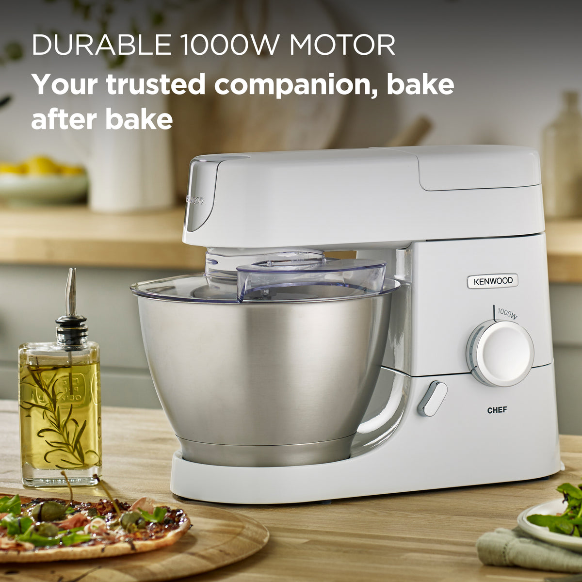 Kenwood 1000 Watt Chef Mixer with stainless steel bowl on wooden kitchen counter near pizza and olive oil bottle