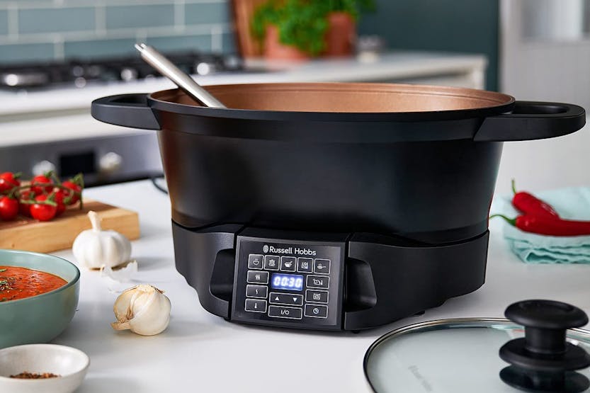 Russell Hobbs Slow Cooker 8 in 1 with digital control panel and ladle inside, on kitchen counter with ingredients nearby