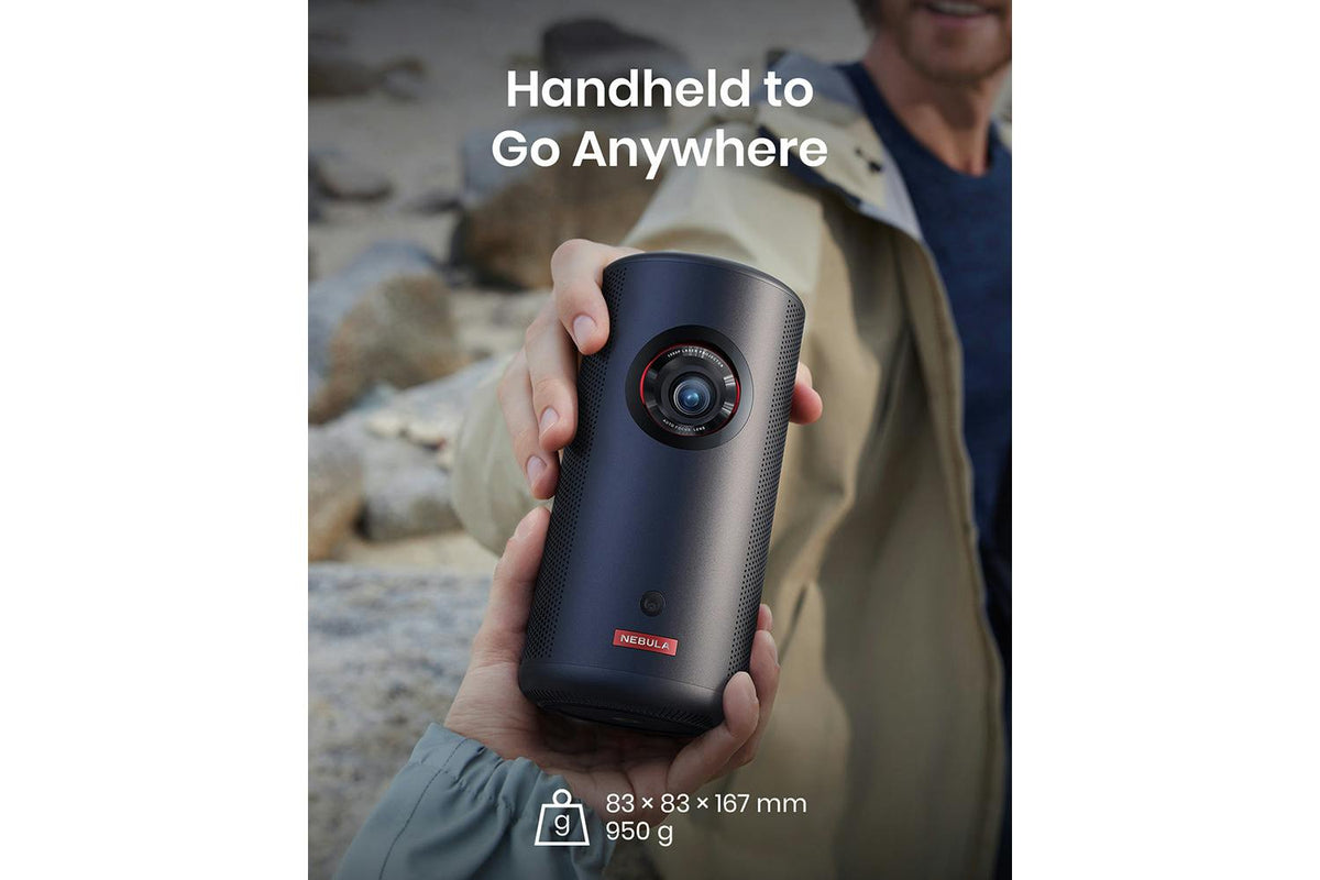 Hands holding a black Nebula Capsule 3 portable projector outdoors with size and weight details visible