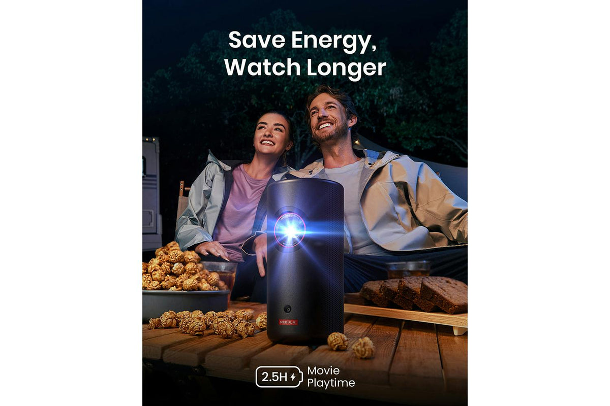 Nebula Capsule 3 projector on a wooden table projecting light with a couple watching outdoors at night