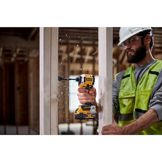 DeWalt 18v compact 1/4 inch impact driver in use drilling into wood by a worker in safety gear