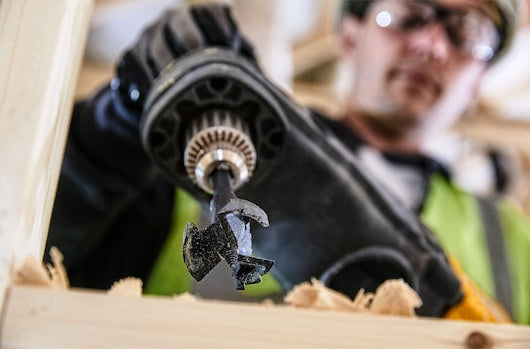 Close-up of a DeWalt Self-Feed Drill Bit 51mm attached to a drill, cutting into wood.