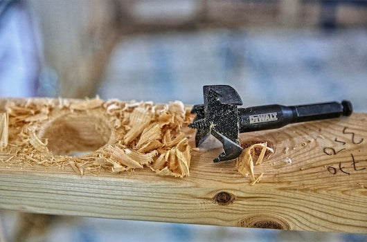 DeWalt 51mm self-feed drill bit resting on wood with a partially drilled hole and wood shavings.
