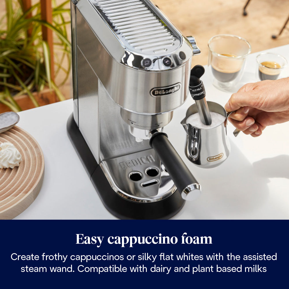 Delonghi Dedica Pump Coffee Machine with steam wand frothing milk in a metal jug on a white table.