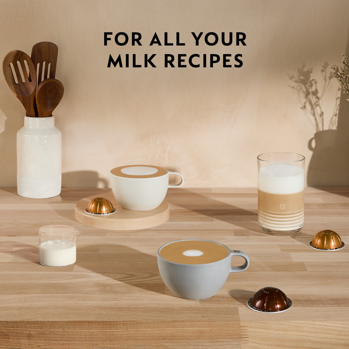 Delonghi Nespresso Vertuo Plus coffee capsules with cups of coffee and milk on a wooden surface