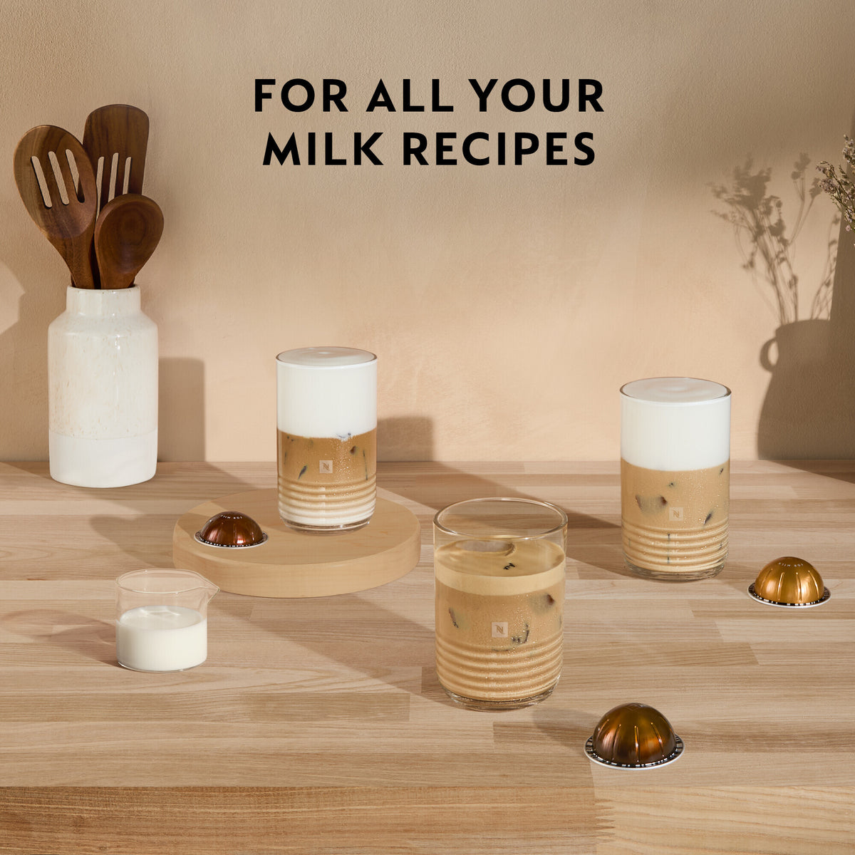 Nespresso Vertuo Pop coffee capsules with iced coffee drinks and milk on a wooden surface