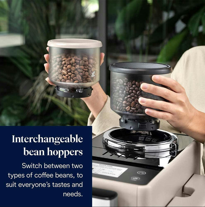 Person holding interchangeable bean hoppers with coffee beans, featuring text about switchable coffee bean types.
