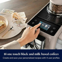 Hand pressing a coffee machine's touch screen with a plate of food and coffee beans in the background.