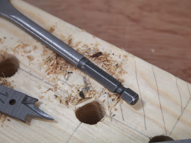 Close-up of a flat bit from the 13-piece Flat Bit Set drilling into wood with wood shavings around.