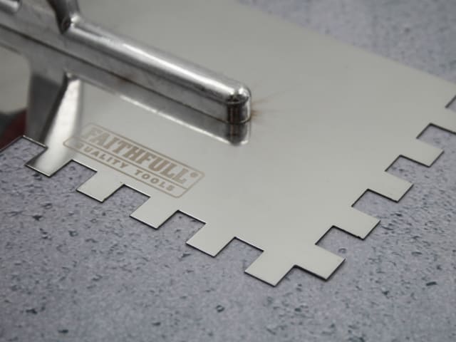 Close-up of the notched edge and handle attachment on the FAI/Full Notched Trowel 13" with Faithfull logo.