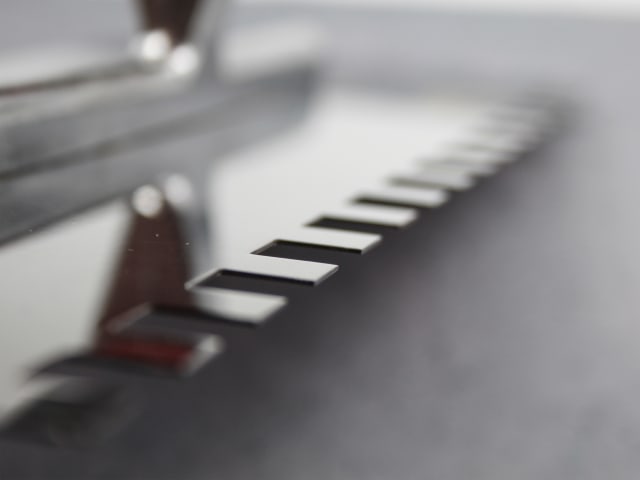 Close-up of the notched edge of the FAI Full Notched Trowel 13" showing rectangular cutouts on the metal blade.