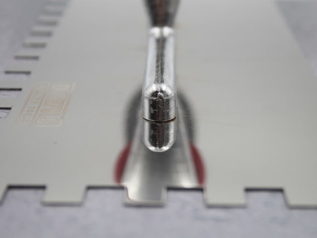 Close-up of the metal blade and handle joint of a 13" full notched trowel with square notches.