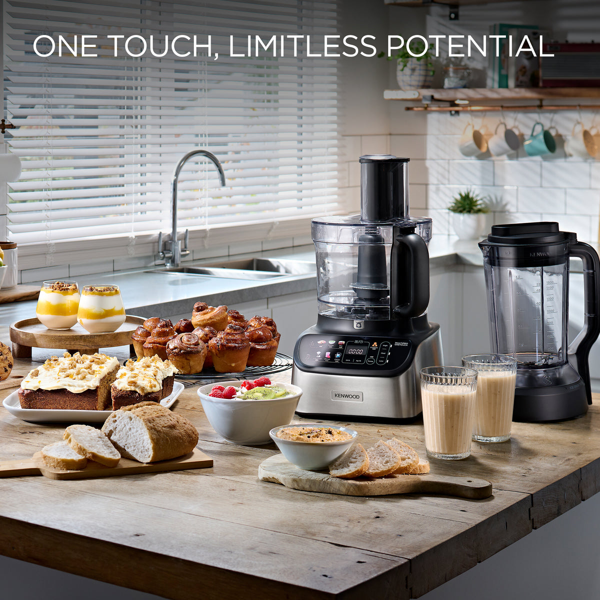 Kenwood 7-in-1 Multipro Express food processor with attachments on kitchen counter surrounded by baked goods and drinks