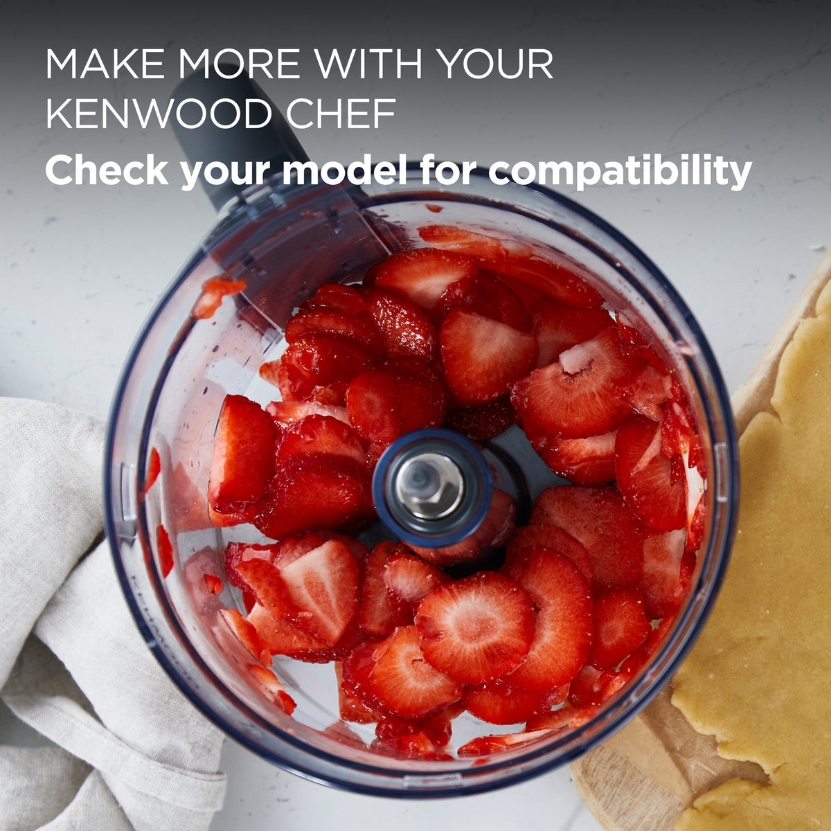 Kenwood Chef food processor attachment bowl with sliced strawberries inside on a kitchen counter.