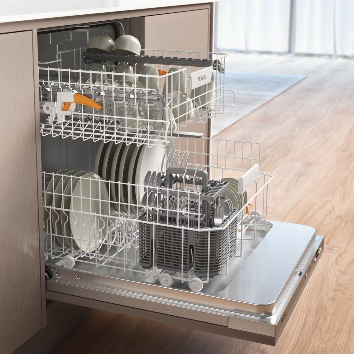 Open Miele fully integrated dishwasher with loaded racks of plates, bowls, and cutlery inside a kitchen unit.