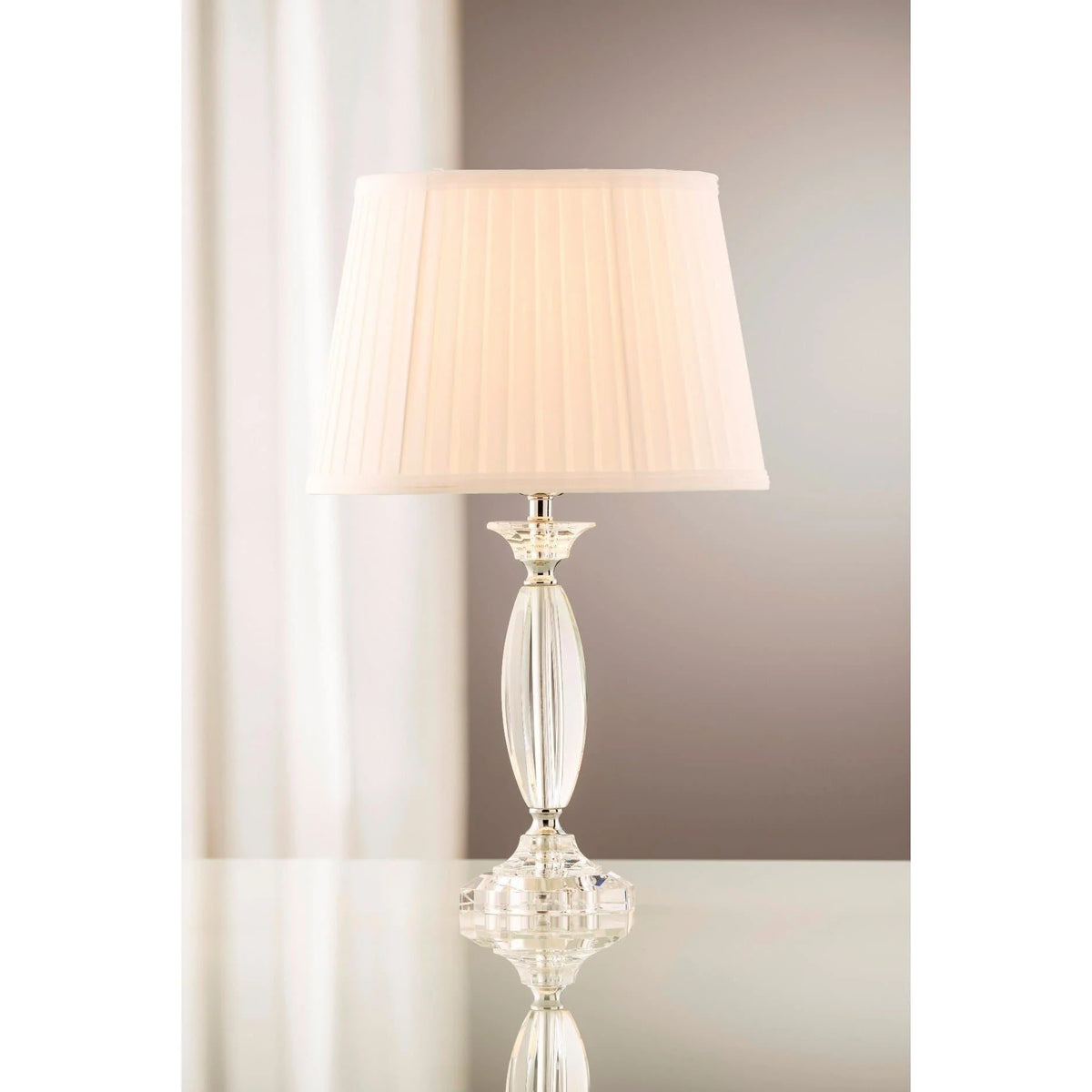 Lyon Lamp & Shade with pleated white fabric shade and clear glass base on a reflective surface