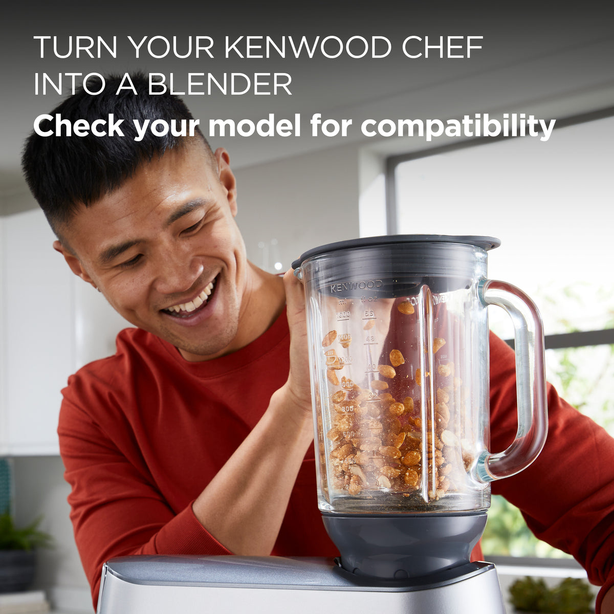 Man in red shirt holding Kenwood Chef Thermoresist Glass Blender Attachment filled with nuts on mixer base