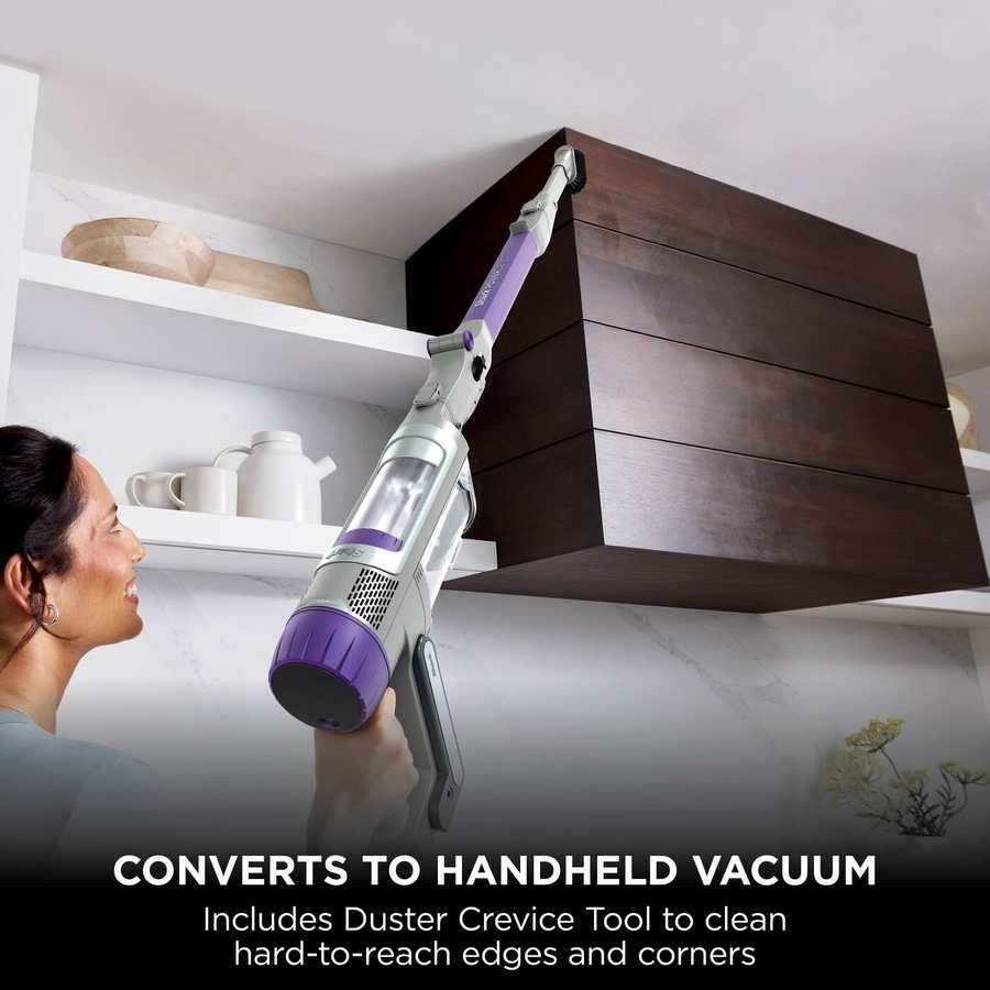 Woman using Shark Cordless Powerdetect Stick Vacuum with duster crevice tool to clean high cabinet edges