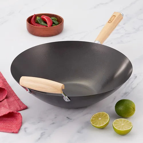 Judge Essentials 33cm non-stick wok with wooden handles on a marble surface with limes and chili peppers nearby