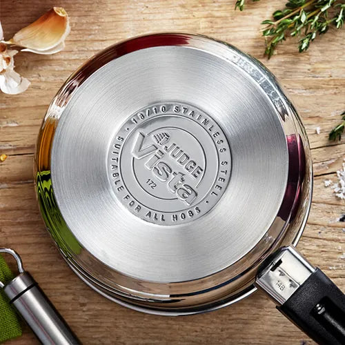 Bottom view of Judge Vista 14cm stainless steel milk pan with black handle on wooden surface.