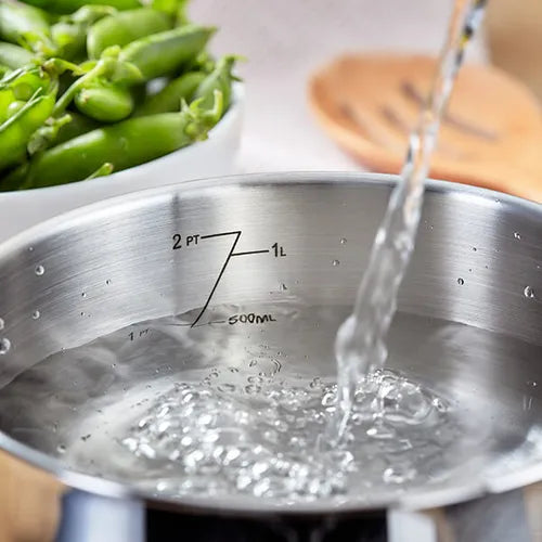 Judge Vista 16cm saucepan with water being poured inside, showing internal volume markings up to 1 liter.