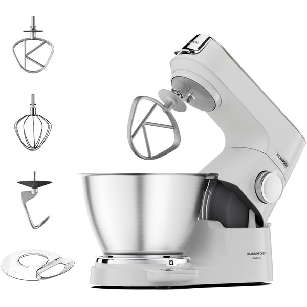 A white stand mixer with a stainless steel bowl and multiple metal attachments shown on a clean white background. The mixer body has visible branding and model text, and the attachments are arranged to the left of the main mixer.