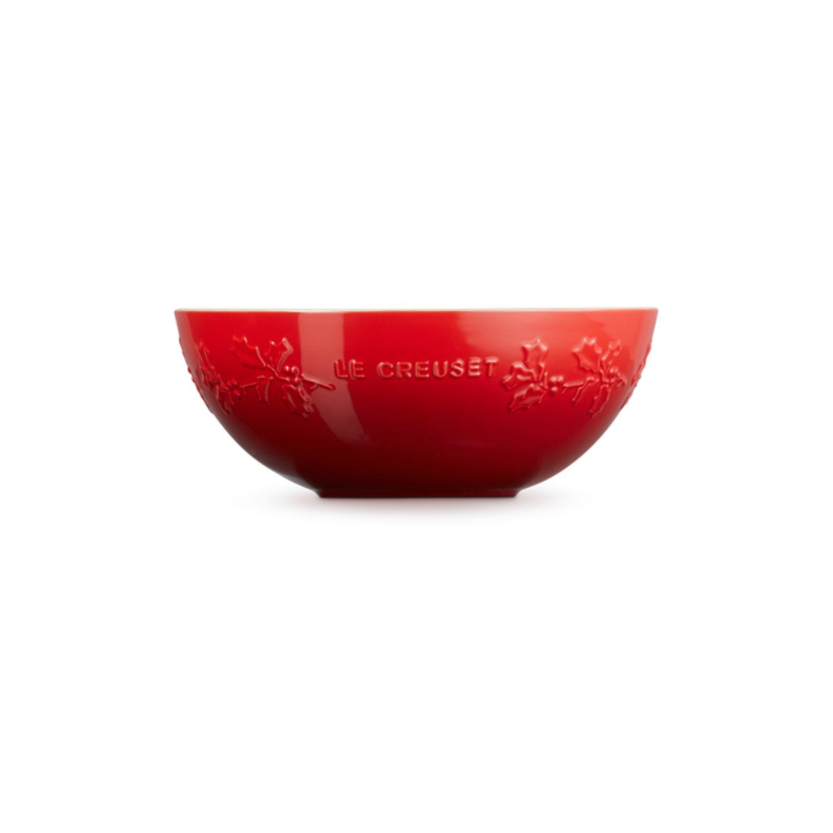 Red Le Creuset mixing bowl with embossed holly design and brand name on the side.