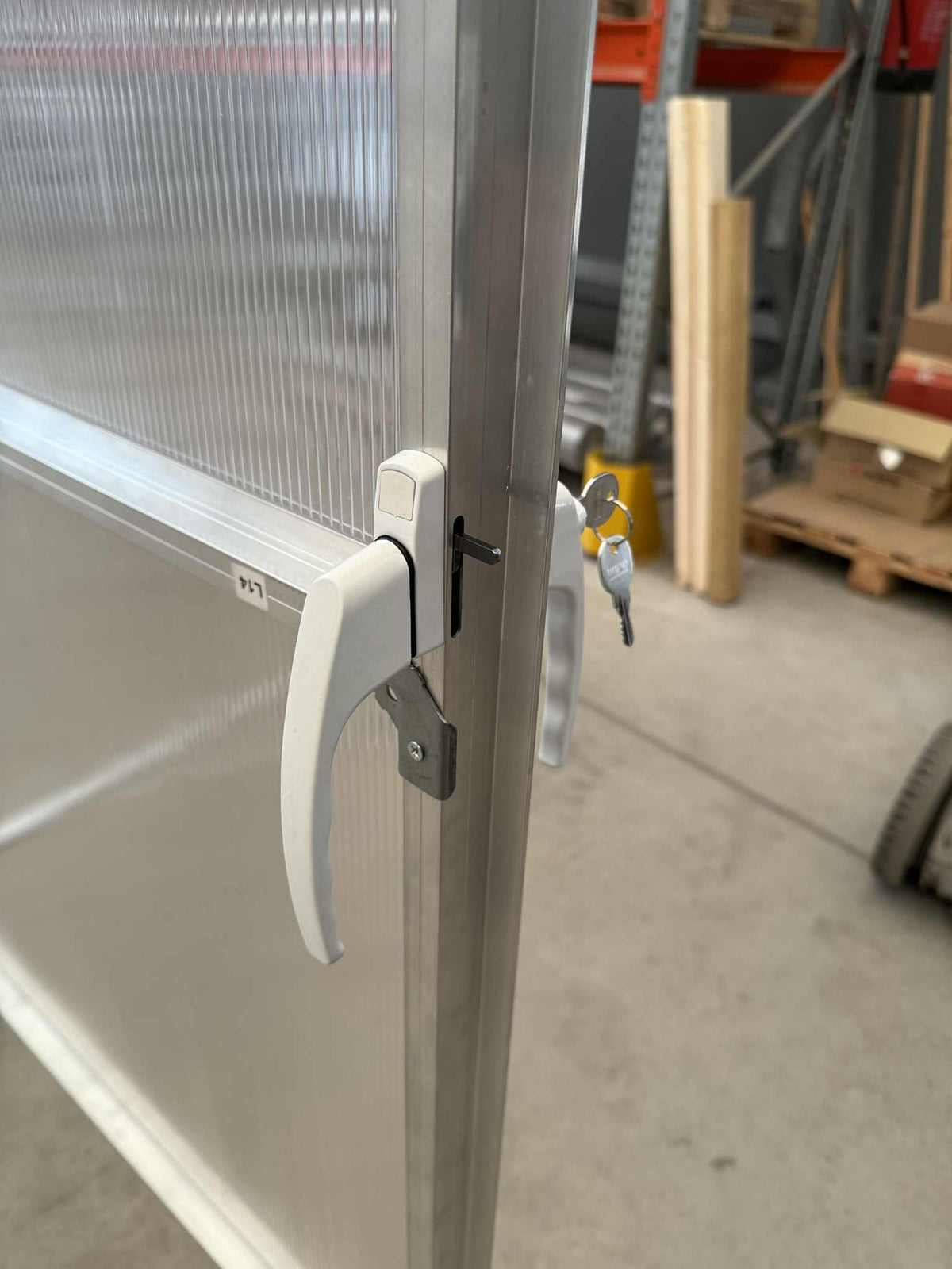 Close-up of the white handle and key lock on the Sigma Lux 3m x 12m polycarbonate greenhouse door panel.