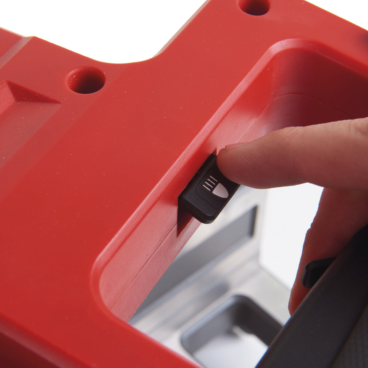 Close-up of a finger adjusting a black switch on the red handle of the Milwaukee M18 Fuel 190mm Mitre Saw