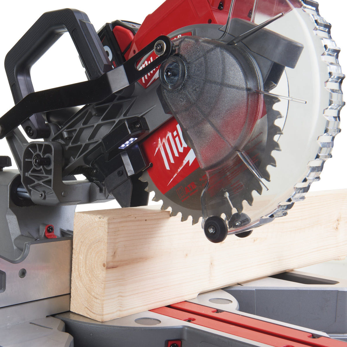 Close-up of Milwaukee M18 Fuel 190mm Mitre Saw blade cutting a wooden plank on the saw base.
