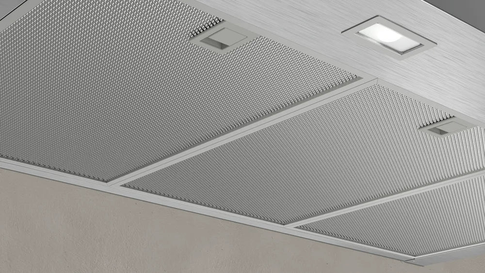 Close-up of the stainless steel mesh filters and built-in lights on the underside of the Neff N50 wall-mounted cooker hood.
