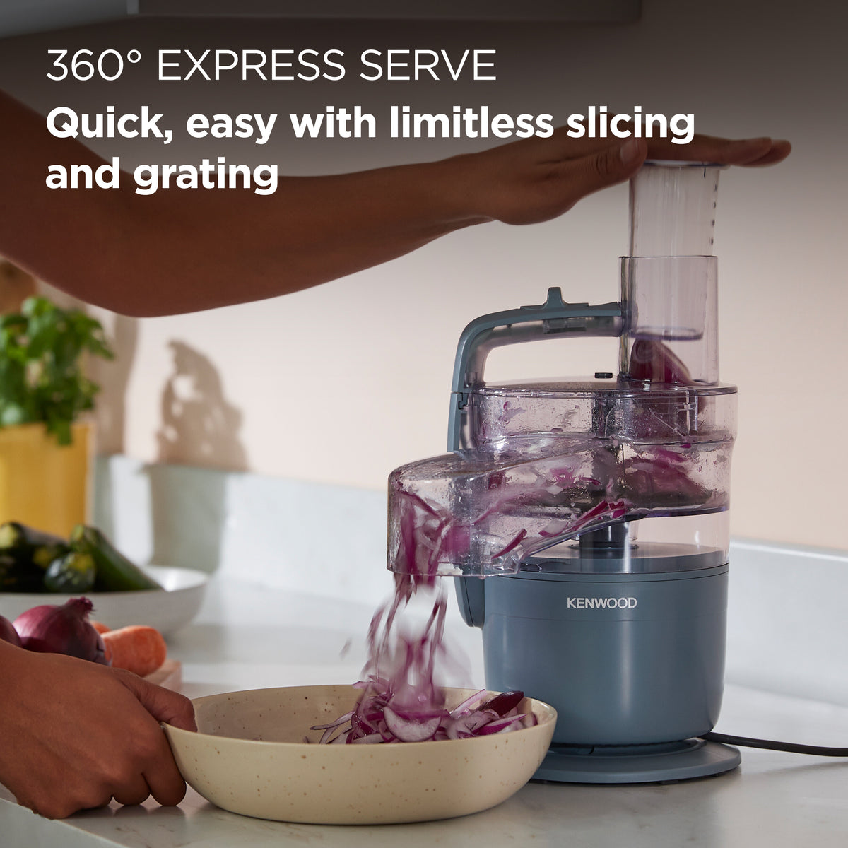 Kenwood Multipro Go Blend food processor in storm blue slicing red onions into a bowl on a kitchen counter