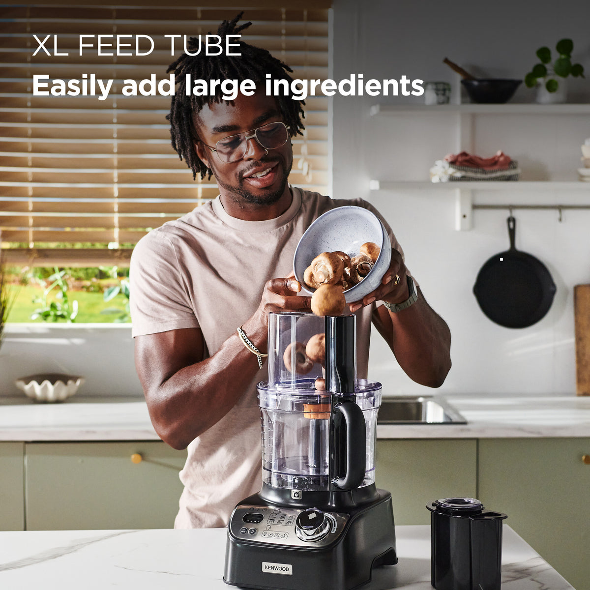 Man pouring mushrooms into the XL feed tube of a Kenwood MultiPro XL Weigh food processor in a kitchen.