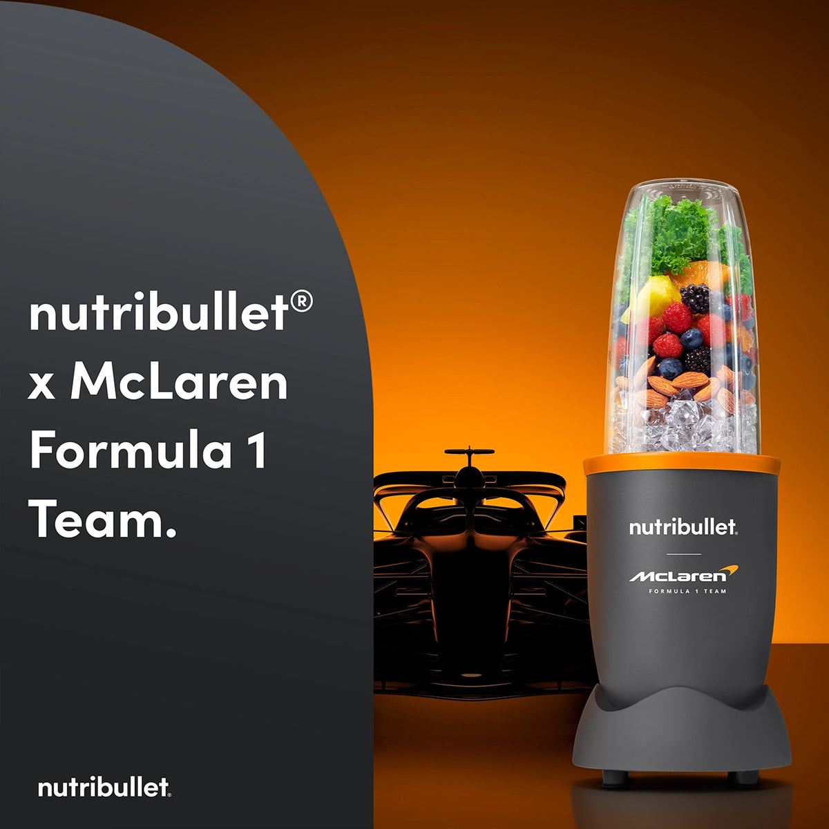 Nutribullet 900w McLaren blender with mixed fruits and greens in the cup, orange background, and race car silhouette.