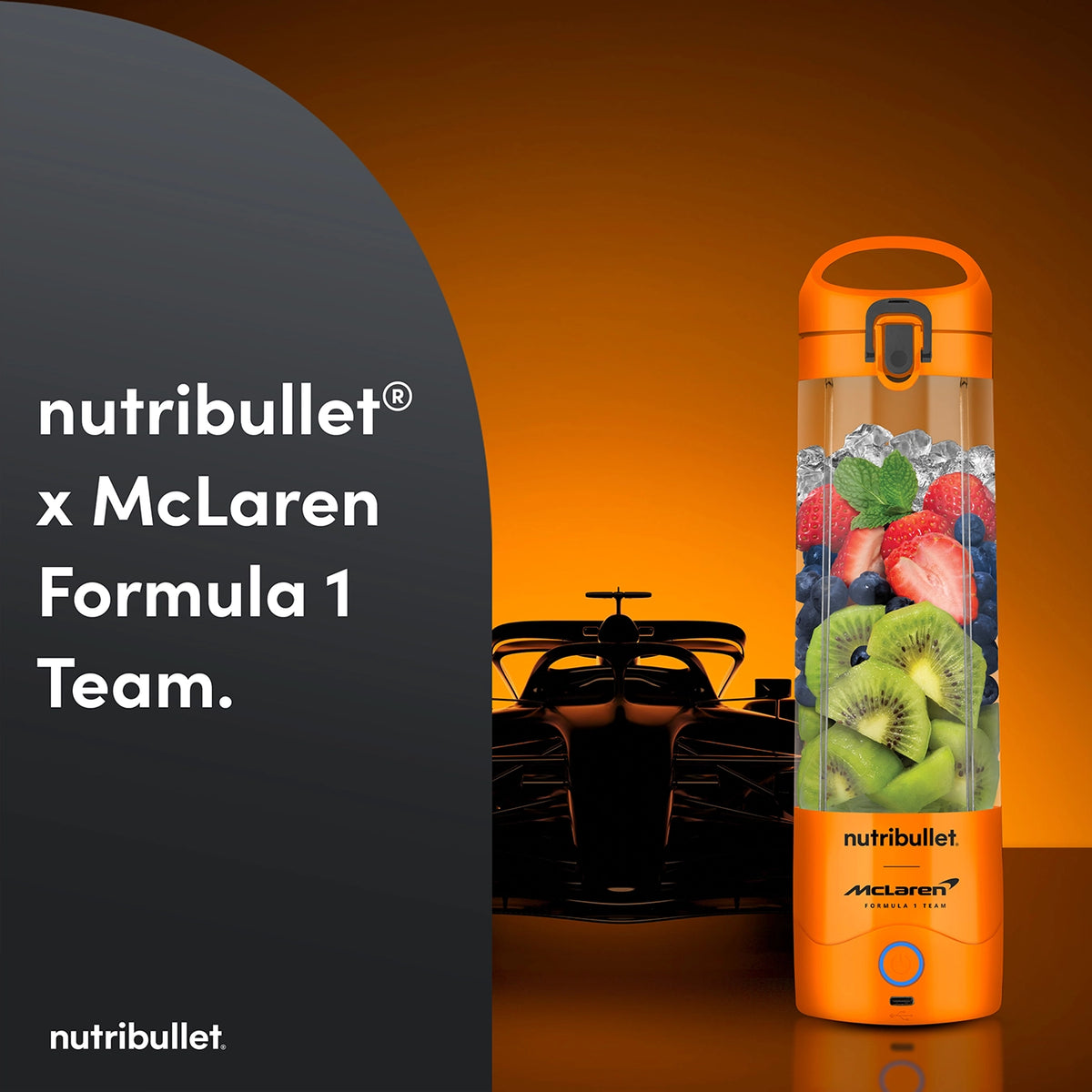 Nutribullet Portable McLaren blender in papaya orange filled with fruit and ice, with a Formula 1 car silhouette behind.