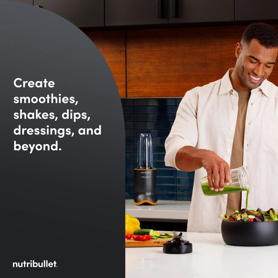 Nutribullet Ultra 1200 McLaren blender with black and orange base on kitchen counter behind man pouring green smoothie.