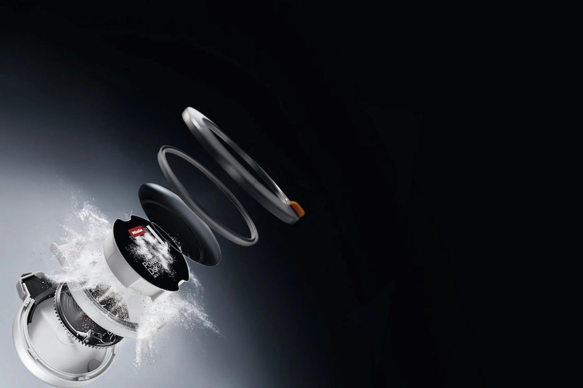 Exploded view of Miele PowerDisk showing internal components and detergent powder release mechanism.