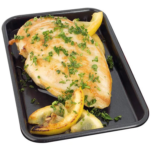 Stellar Bakeware non-stick baking tray with cooked chicken breast garnished with herbs and lemon wedges