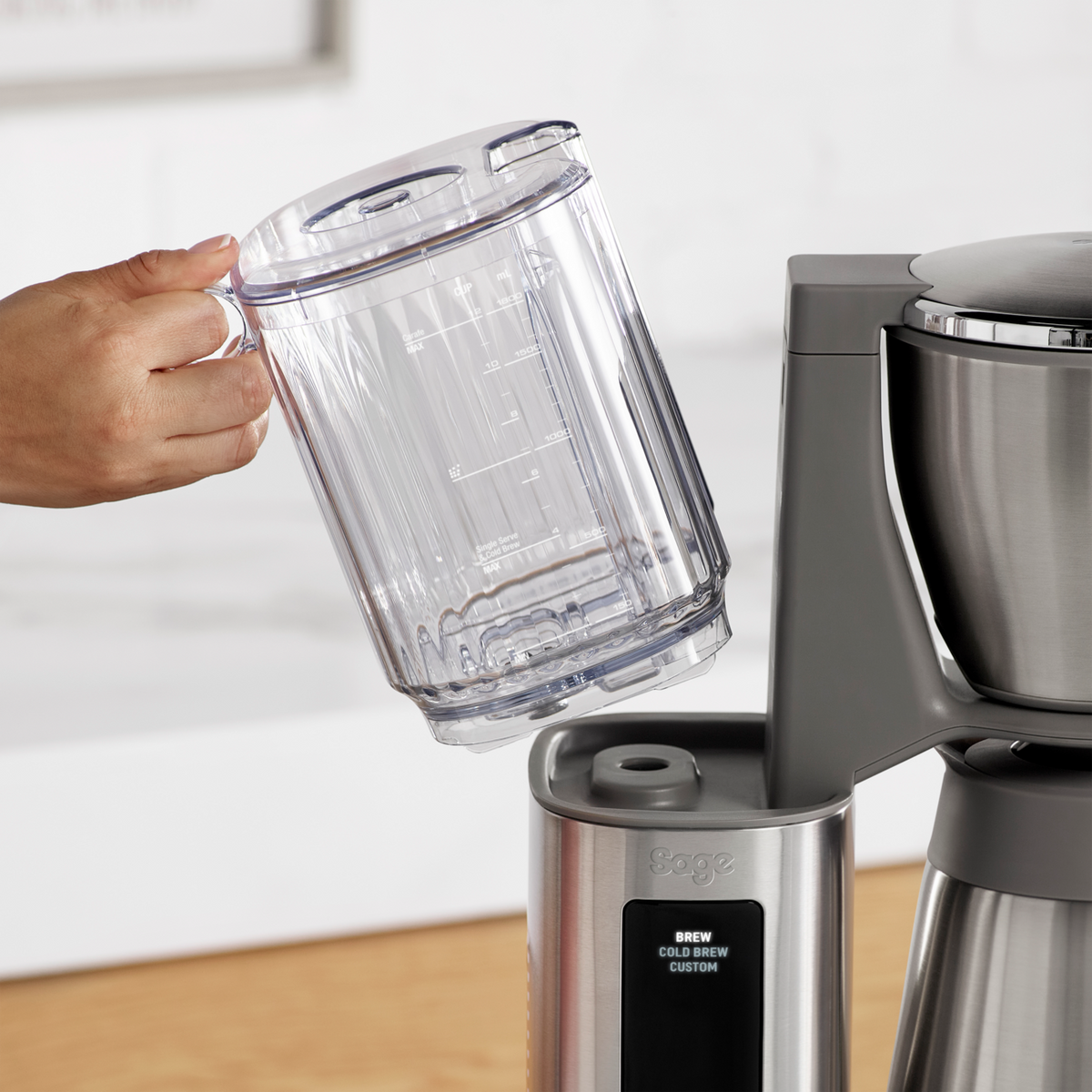 Hand holding the clear water tank being removed from the Sage Precision Brewer Thermal Brushed Steel coffee maker.