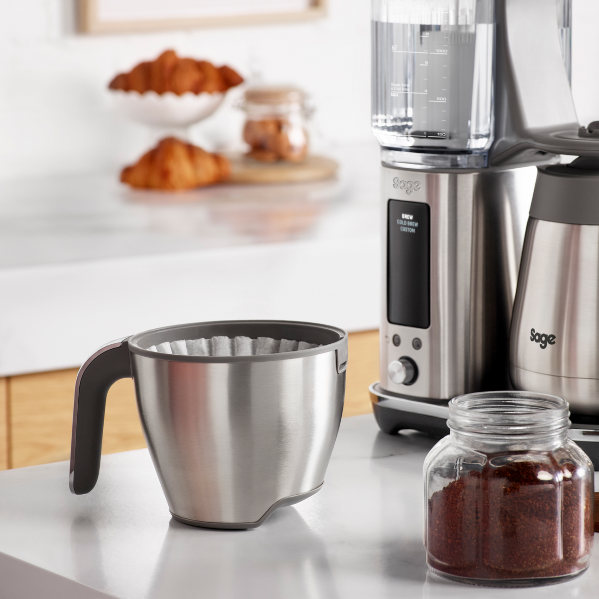 Sage Precision Brewer Thermal brushed steel filter basket with coffee maker and jar of ground coffee on counter