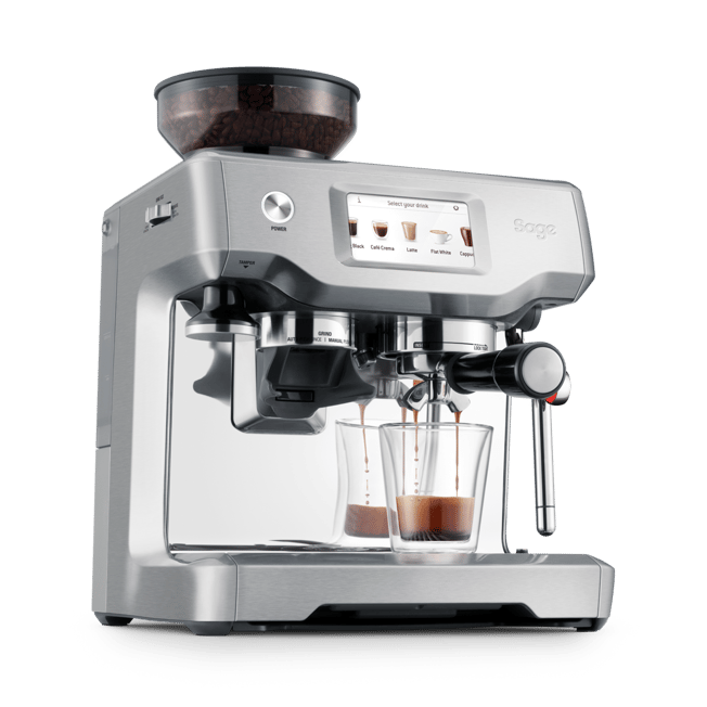 A silver Sage espresso machine with a transparent bean hopper on top, shown with two glass cups filled with espresso on a clean white background.