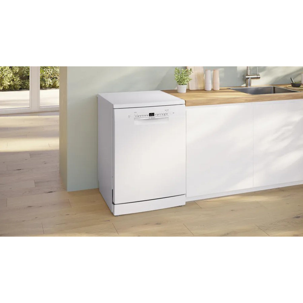 Bosch Series 2 white freestanding dishwasher installed next to a kitchen counter with wooden countertop and sink